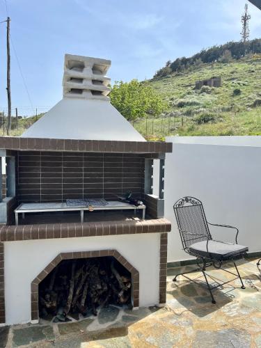 a patio with a brick fireplace and a chair at Villa Eftychia Serene Getaway with Hot Tub in a Quiet Location in Kissamos
