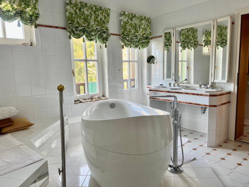 a large white bathroom with a tub and a sink at Dietrichsteinerhof Apartments & Rooms in Faak am See