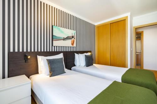 two beds in a hotel room with striped walls at WHome Panoramic View with Elevator, AC, Garage perfect for Families & Business Travellers in Lisbon