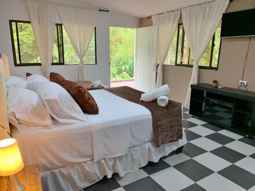 a bedroom with a large white bed and a checkered floor at Hotel La Casablanca Tayrona in Calabazo