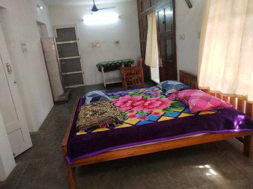 a bedroom with a bed with a purple blanket on it at Mayurapriya Inn in Chennai