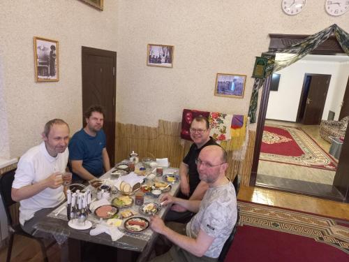 a group of men sitting around a table with food at Yulduz Hotel in Khiva
