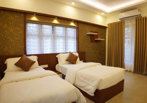 a hotel room with two beds and a window at Feliz Homes Kottakkal in Kottakkal