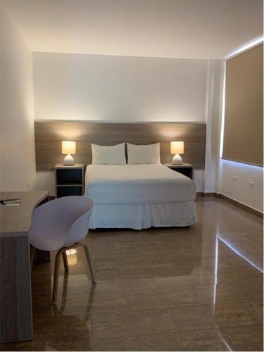 a bedroom with a bed and two tables and a chair at HOTEL DIANA PRINCESS in San Pedro Sula
