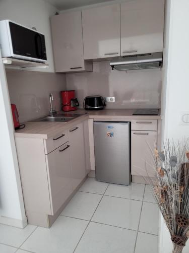 Elle comprend une petite cuisine avec des placards blancs et un réfrigérateur. dans l'établissement Appartement Le Victoria Saint-Aygulf Fréjus, à Saint-Aygulf