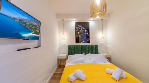 a bedroom with a yellow bed with two white pillows at Apartmani Bokin in Bol