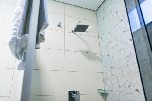 La salle de bains est pourvue d'une douche avec du carrelage blanc. dans l'établissement Royal Hotel, à Tailandia