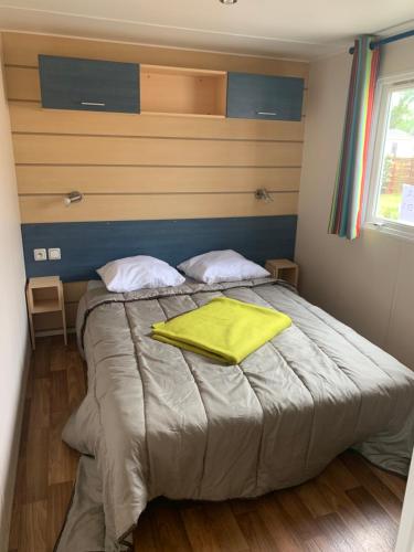 Un dormitorio con una cama con una toalla amarilla. en Camping l’Europe en Vic-la-Gardiole