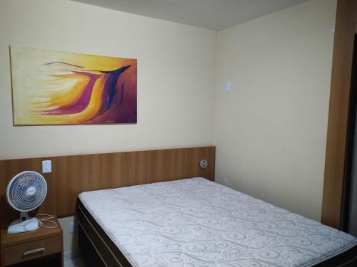 ein Schlafzimmer mit einem Bett und einem Gemälde an der Wand in der Unterkunft 1406 AP 2 Quartos Shopping, Banheira de Hidro privativa , bebidas liberadas nas piscinas e internet no ap, proximo ao shopping singapura in Caldas Novas