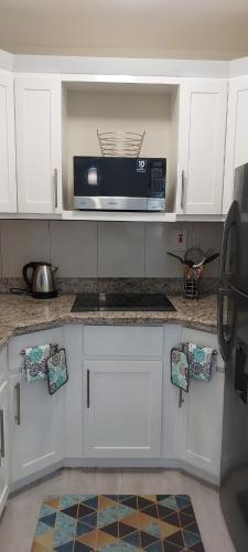 a kitchen with white cabinets and a microwave at Almond Grove at Sand Castle in Ocho Rios