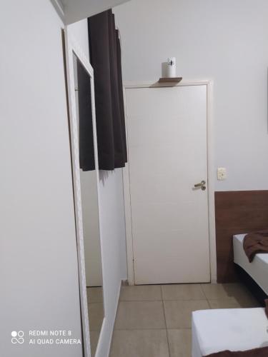 Pokój z białymi drzwiami i łóżkiem w obiekcie Pousada Quarto com ventilador,ar frigobar e garagem w mieście Aparecida
