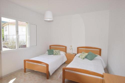 a bedroom with two beds and a table and a window at Apartamento Carnota in Carnota