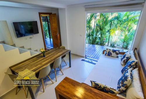 a living room with a wooden table and a large window at SUN7 in Morro de São Paulo