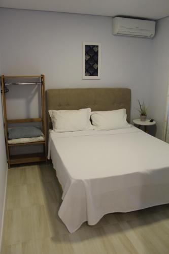 a bedroom with a large white bed with white pillows at Hotel e Pousada Magic in Penha