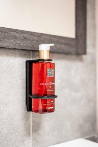 a bottle of red soap sitting on top of a sink at L'ARTiste in Lessines