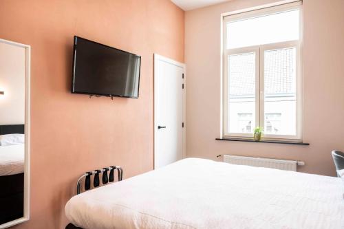 a bedroom with a bed and a flat screen tv on the wall at L'ARTiste in Lessines