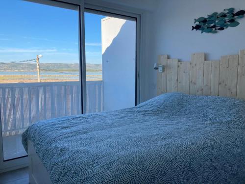 una camera con un letto blu e una grande finestra di Duplex terrasse vue mer accès plage et piscine... a Frontignan