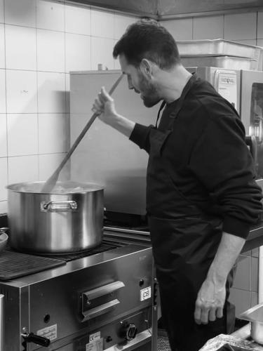 a man stirring a pot in a kitchen at LOCANDA PODERE LE VIGNE in Radda in Chianti