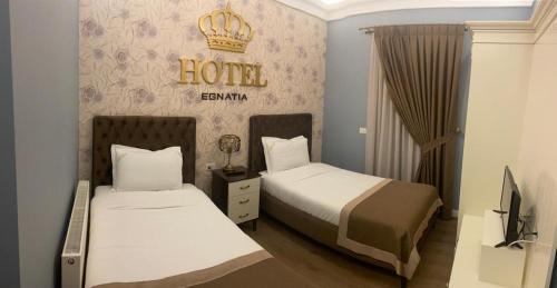 a hotel room with two beds and a sign on the wall at Hotel Egnatia in Bilisht