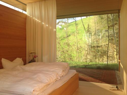 ein Schlafzimmer mit einem Bett und einem großen Fenster in der Unterkunft Haus am Felsen, Ferien in Vorarlberger Architektur in Bregenz