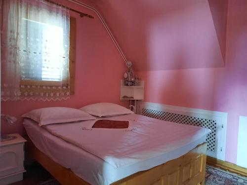 a bedroom with a bed with a pink wall at Antal Apartmans Lunca de Sus Kulcsosház Gyimesfelsőlok in Lunca de Sus