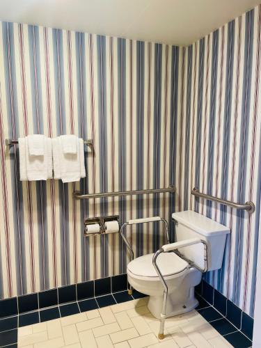 a bathroom with a toilet and towels on a striped wall at America's Best Value Inn Sandpoint in Sandpoint