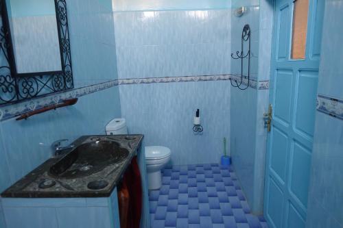 Baño azul con lavabo y aseo en Maison Vallée Du Ziz en Ouled Aissa