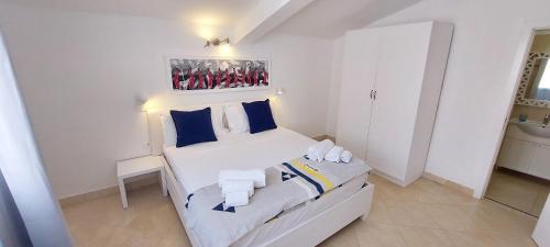 a bedroom with a white bed with blue pillows at Branco Suites - Rooms & Holiday Apartments in Santa Maria