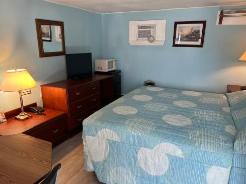 een slaapkamer met een bed, een dressoir en een televisie bij Budget Inn Motel Suites Somers Point in Somers Point