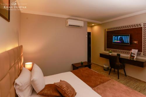 a bedroom with a bed and a desk and a television at Khan Duidar Inn - Pyramids View Rooftop in Cairo