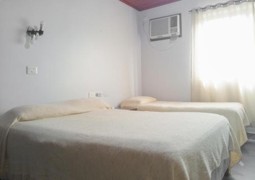 two beds in a white room with a window at Hotel Mola in Puerto Iguazú