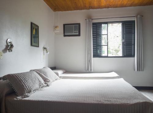 a white bedroom with a bed and a window at Hotel Mola in Puerto Iguazú