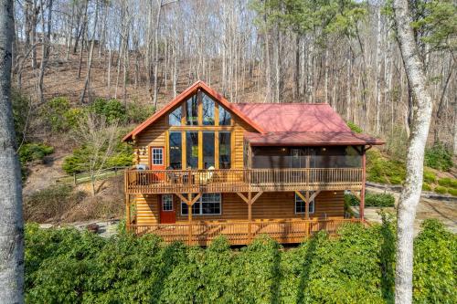 a log cabin with a deck in the woods at Bear Print Mountain Lodge in Waynesville