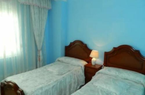 2 camas en un dormitorio con paredes azules en Apartamento Puerto Finisterre, en Finisterre