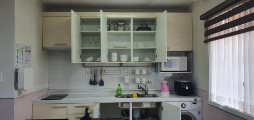 a kitchen with white cabinets and a sink at Jeju Skyline Pension in Jeju