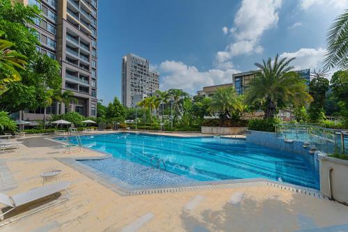 a large swimming pool with palm trees and buildings at CM Serviced Apartment in Shenzhen