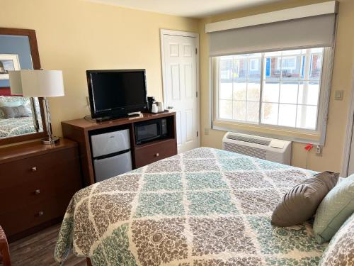 a bedroom with a bed and a flat screen tv at Scarborough Beach Motel in Narragansett