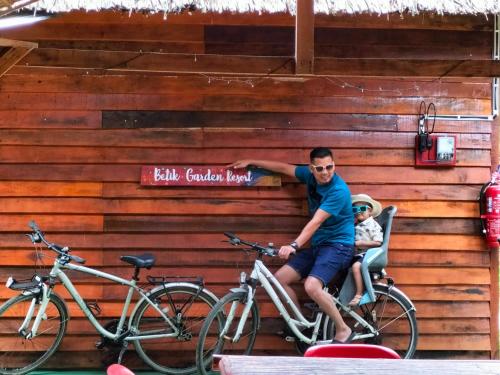 a man sitting on a bike next to two bikes at Betik Garden Home in Machang