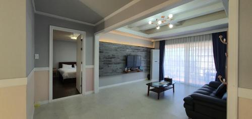 a living room with a couch and a bedroom at Jeju Skyline Pension in Jeju