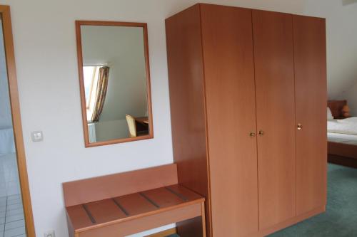 a bedroom with a wooden cabinet and a mirror at Hotel Ideal in Lübeck