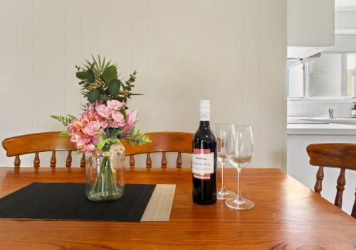 a bottle of wine sitting on a table with two glasses at Metung Akora 2Bdrm Apartment 1 - Pets & Boats welcome! Close to Town, Free Wifi & Netflix in Metung