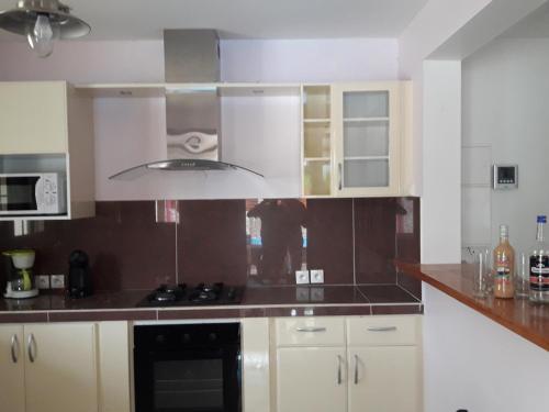 a kitchen with white cabinets and a stove top oven at Aux petits flots in Le Gosier