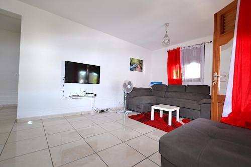 a living room with a couch and a tv at Aux petits flots in Le Gosier