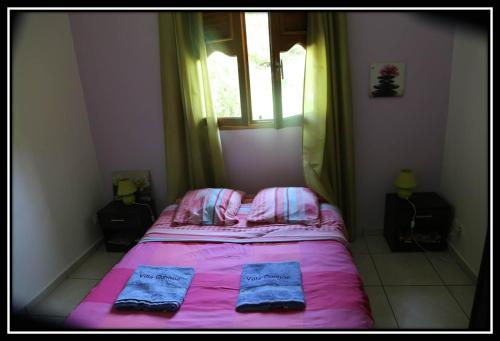 a bedroom with a bed with pink sheets and a window at Aux petits flots in Le Gosier