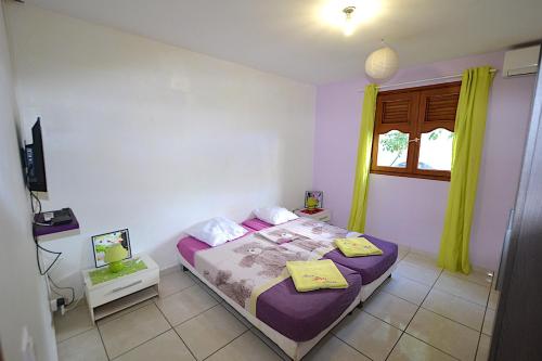 a bedroom with a bed with purple sheets and a window at Aux petits flots in Le Gosier