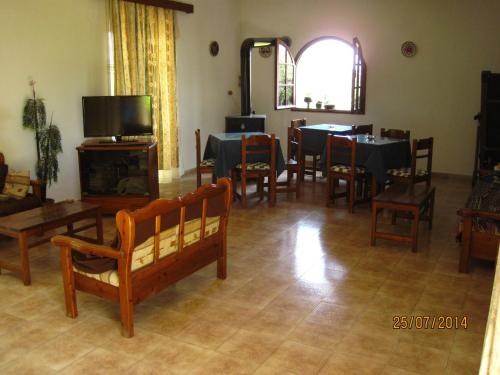 a living room with tables and chairs and a television at Hotel Narkissos in Archangelos