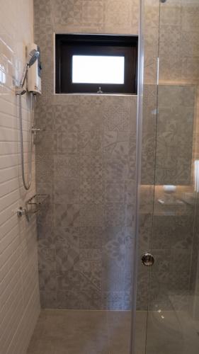 a bathroom with a glass shower with a window at BAAN 125 STAY Phuket in Phuket Town