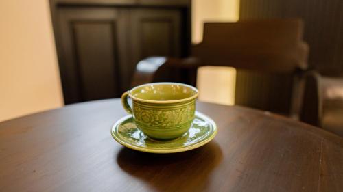 a green coffee cup sitting on a wooden table at BAAN 125 STAY Phuket in Phuket Town