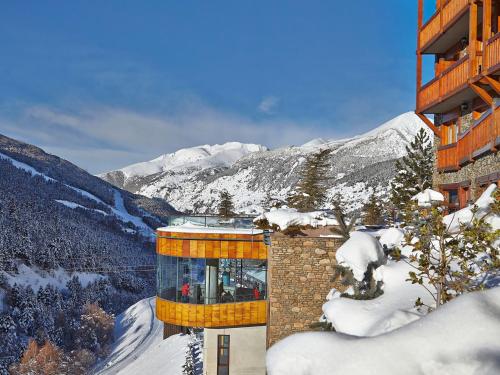 a building in the snow with mountains in the background at Sport Hotel Village in Soldeu