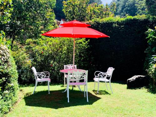 a table and two chairs with a red umbrella at Miliya Guest House in Nuwara Eliya